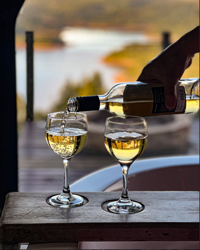 Vinho branco sendo servido no deck com vista para o lago